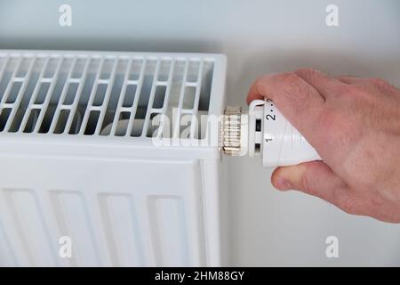 Die Temperatur am Heizkörper-Thermostat von Hand einstellen und den Heizkörper-Regler drehen, um die Wärme zu Hause zu steuern Stockfoto