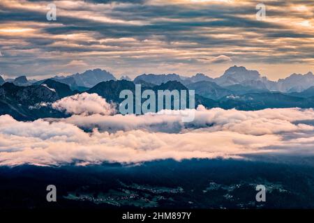 Dolomitenrücken und Gipfel rund um Falcade, bedeckt mit Wolken, im Biois-Tal, von oberhalb des Valles-Passes bei Sonnenaufgang gesehen. Stockfoto