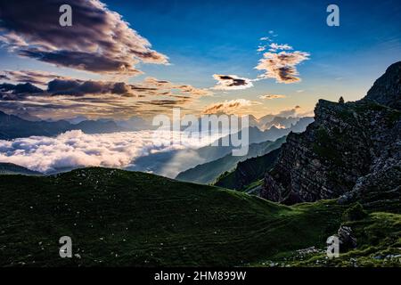 Dolomitenrücken und Gipfel rund um Falcade, bedeckt mit Wolken, im Biois-Tal, von oberhalb des Valles-Passes bei Sonnenaufgang gesehen. Stockfoto