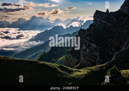 Dolomitenrücken und Gipfel rund um Falcade, bedeckt mit Wolken, im Biois-Tal, von oberhalb des Valles-Passes bei Sonnenaufgang gesehen. Stockfoto