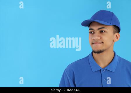 Junger Mann in Lieferuniform auf blauem Hintergrund Stockfoto