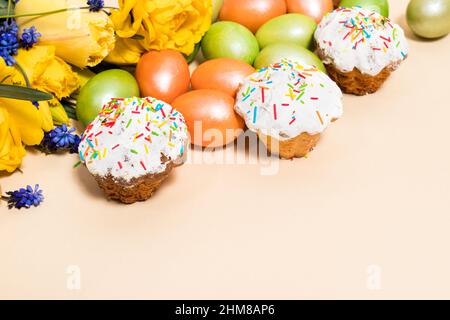Osterkuchen, Eier und gelbe Tulpen auf beigem Hintergrund mit Platz für Text. Stockfoto
