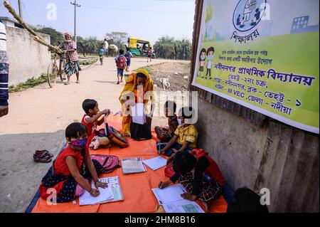 Die Regierung des Bundesstaates Westbengalen hat ‘Paray Shikshalaya’ vom 7th. Eine gemeindebasierte Schularbeit in Nachbarschaften, die sich an Grundschüler richtet, um die programmierten Ziele zu erreichen, besteht darin, einen großen Teil der Schüler zurückzuholen, die in den letzten zwei Jahren aufgrund der Schließung von Schulen aufgrund von Covid-19 aus dem formalen Bildungssystem ausgefallen sind. Die Vorschulklasse einer an der Grenze zwischen Indien und Bangladesch angrenzenden Grundschule wird auf einer leeren Straße neben dem Zaun bei Nabin Nagar durchgeführt, es kommen gelegentlich Haustiere. (Foto von Soumyabrata Roy/Pacific Press) Stockfoto