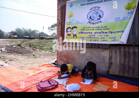 Die Regierung des Bundesstaates Westbengalen hat ‘Paray Shikshalaya’ vom 7th. Eine gemeindebasierte Schularbeit in Nachbarschaften, die sich an Grundschüler richtet, um die programmierten Ziele zu erreichen, besteht darin, einen großen Teil der Schüler zurückzuholen, die in den letzten zwei Jahren aufgrund der Schließung von Schulen aufgrund von Covid-19 aus dem formalen Bildungssystem ausgefallen sind. Die Vorschulklasse einer an der Grenze zwischen Indien und Bangladesch angrenzenden Grundschule wird auf einer leeren Straße neben dem Zaun bei Nabin Nagar durchgeführt, es kommen gelegentlich Haustiere. (Foto von Soumyabrata Roy/Pacific Press) Stockfoto