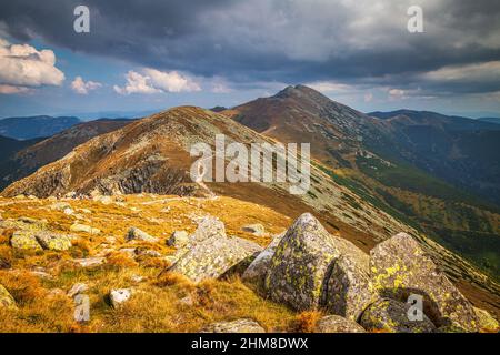 Bergige Landschaft mit Hügeln und Tälern an einem sonnigen Tag im Herbst. Dumbier, der höchste Gipfel des Nationalparks Niedere Tatra im Hintergrund Stockfoto