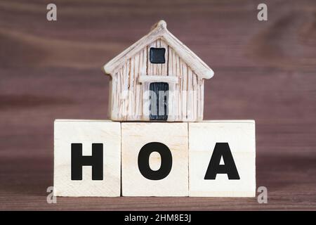 Abkürzung HOA aus hölzernen Buchstabenblöcken mit einem Miniaturhaus auf der Oberseite. Hausbesitzer Assoziationskonzept. Stockfoto