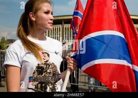 Moskau, Russland. 2nd. August 2014 Aktivistin der NOD-Bewegung - Maria hält die Flagge von Noworossiya bei einer Kundgebung zur Unterstützung des Donbass nannte Noworossiya "die Schlacht um Donezks Rus!" In Moskau, Russland. Das T-Shirt zeigt das Porträt von Igor Strelkov, dem ehemaligen Verteidigungsminister der Volksrepublik Donezk (DPR) Stockfoto