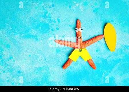Lustige Seesterne-Figur mit einem gelben Surfbrett, das auf einem hellblauen Hintergrund liegt und Wasser imitiert. Kreatives Surf-Urlaubskonzept. Stockfoto