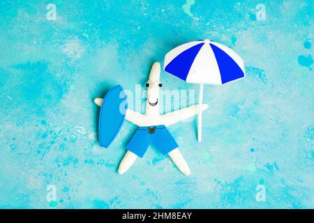 Lustige weiße Seesterne mit einem blauen Surfbrett und einem Sonnenschirm, der auf einem hellblauen Hintergrund liegt und Wasser imitiert. Kreatives Surftrip-Konzept. Stockfoto