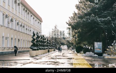 Gelendzhik, Russland, 24. Januar 2022: Stadtlandschaft mit Menschen, die in der Wintersaison am Ufer neben der Stadtverwaltung spazieren. Stockfoto