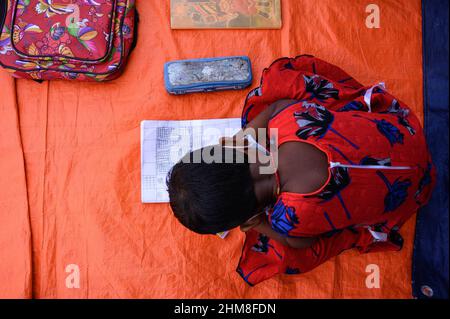 Nabin Nagar, Westbengalen, Indien. 7th. Februar 2022. Die Regierung des Bundesstaates Westbengalen hat am 7th. Februar „˜Paray Shikshalaya“ ins Leben gerufen, Eine gemeindebasierte Schularbeit in Nachbarschaften, die sich an Grundschüler richtet, um die programmierten Ziele zu erreichen, besteht darin, einen großen Teil der Schüler zurückzuholen, die in den letzten zwei Jahren aufgrund der Schließung von Schulen aufgrund von Covid-19 aus dem formalen Bildungssystem ausgefallen sind. Die Vorschulklasse einer an der Grenze zwischen Indien und Bangladesch angrenzenden Grundschule wird auf einer leeren Straße neben dem Zaun bei Nabin Nagar durchgeführt, es kommen gelegentlich Haustiere. (Kredit Stockfoto