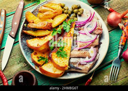 Stücke von gesalzenem Hering mit gebackenen Kartoffeln und Toast. Stockfoto
