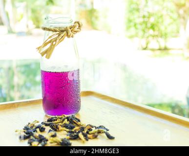 Butterfly Erbsensaft wird in ein Holztablett mit getrockneten Schmetterlingsblüten gelegt. Thailändische Kräuter für die Gesundheit Stockfoto