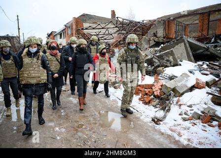 Schyrokyne, Ukraine. 08th. Februar 2022. Annalena Baerbock (Bündnis 90/die Grünen, 4th v.r.), Außenministerin, informiert sich über die Lage in der Konfliktregion Donbass im verlassenen Dorf Schyrokyne an der Frontseite zwischen der ukrainischen Armee und den russisch unterstützten Separatisten. Dabei geht sie an zerstörten Gebäuden vorbei. Außenminister Baerbock ist zu einem zweitägigen Besuch in der Hauptstadt und der Ostukraine. Quelle: Bernd von Jutrczenka/dpa/Alamy Live News Stockfoto