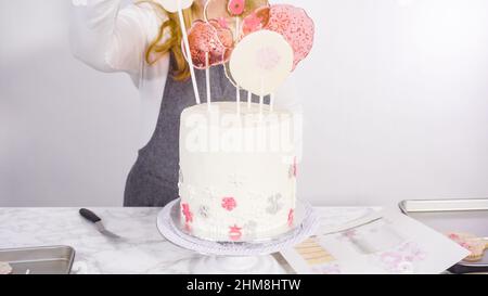 Einfügen von großen Lutscher mit Schneeflocken in den hohen Weiße, runde Kuchen als Dekoration. Stockfoto