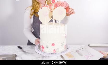 Einfügen von großen Lutscher mit Schneeflocken in den hohen Weiße, runde Kuchen als Dekoration. Stockfoto