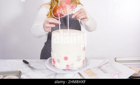 Einfügen von großen Lutscher mit Schneeflocken in den hohen Weiße, runde Kuchen als Dekoration. Stockfoto