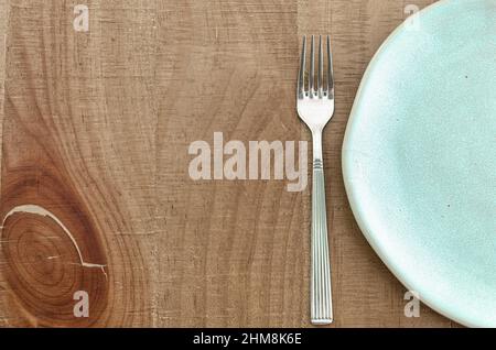 Leeren Sie den Teller mit der Gabel auf einem Holztisch. Draufsicht. Stockfoto