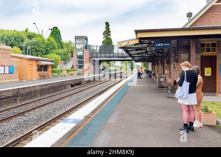 Am Bowral Bahnhof in den Southern Highlands von New South Wales, Australien, wartet ein junger Mann an einem Wochenende auf dem Bahnsteig auf einen Zug mit Zugverbindung nach Sydney Stockfoto