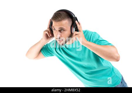 Junger Mann, der mit einem schwarzen Kopfhörer auf weißem Hintergrund Musik hört Stockfoto