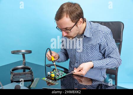 Porträt des professionellen Computerexperten, technischer Autor, der mit dem Motherboard auf blauem Hintergrund isoliert arbeitet Stockfoto