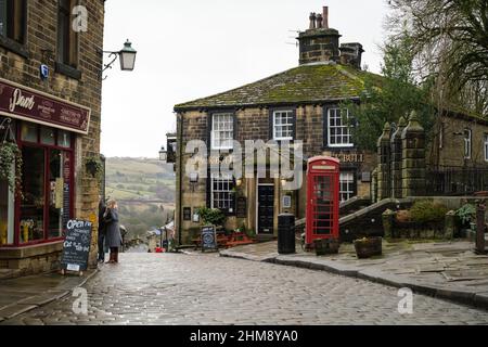 Haworth, Großbritannien: Main Street in Howarth, West Yorkshire, zieht Touristen aus der ganzen Welt wegen seiner Verbindungen zu den Bronte Sisters an. Stockfoto