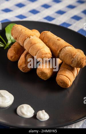 Cheese Fingers, die typische venezolanische Vorspeise namens tequeños auf einem schwarzen Teller Stockfoto