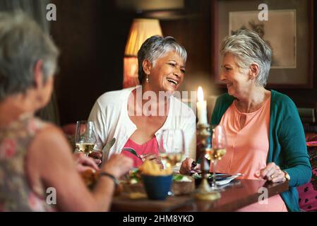 Lustige Geschichten mit guten Freunden teilen. Eine kurze Aufnahme einer Gruppe älterer Freundinnen, die ein Mittagessen genießen. Stockfoto