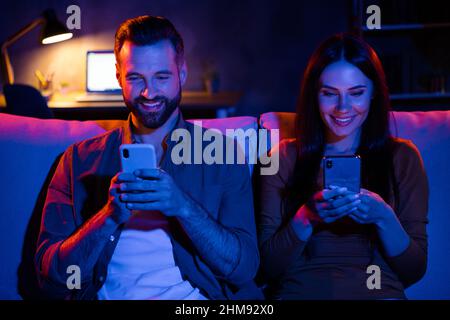 Foto von Freunden Studenten Dame Kerl sitzen Couch Abend Nacht Freizeit verwenden Smart-Gerät Blogging Web-Shopping Stockfoto