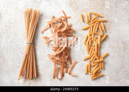 Vollkorn-Pasta-Sortiment, Spaghetti, Tagliatelle und Penne Rigate, gesunde Nudeln mit Ballaststoffen, Eiweiß, B-Vitaminen und Mineralstoffen, Draufsicht aus abov Stockfoto