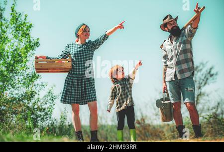 Menschen, die im Garten des Hinterhofs auftreffen. Familienbauern zeigen auf den Himmel. Familiengartenarbeit im Garten des Hinterhofs. Lifestyle und Familienleben. Stockfoto