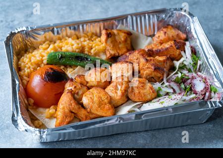 Nehmen Sie türkischen Chicken Kebab in Aluminiumfolie Lebensmittelbehälter weg. Teller Herausnehmen. Bereit zu essen und zu servieren. Stockfoto