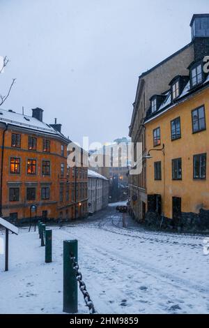 Verschneite, farbenfrohe, traditionelle schwedische Straße im Abendlicht in Sodermalm, Stockholm, Schweden. Hochwertige Fotos. Stockfoto