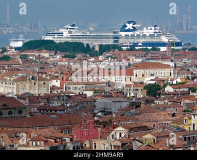 Blick vom Markusturm in Venedig über die Dächer der Stadt bis zum Pier. Ein Kreuzschiff hat dort angedockt und ragt aus dieser Perspektive sogar über Häuser und Bäume. Stockfoto