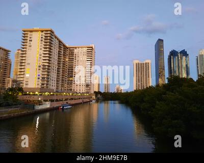 Sunny Isles, USA - 22. März 2021: Hochhäuser und grüne Bäume entlang des Flusses am blauen Himmel Stockfoto