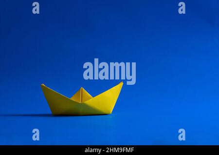 Gelbes Origami-Boot auf blauem Hintergrund horizontal Stockfoto