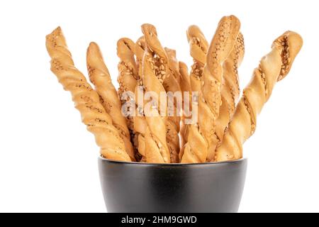 Mehrere leckere GRISsini-Brotstäbchen in einer schwarzen Tasse, Nahaufnahme, isoliert auf Weiß. Stockfoto