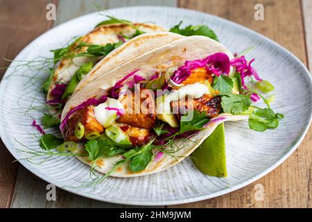 Tacos mit Lachs, eingelegtem Rotkohl, Wasabi-Mayo und Erbsensprossen Stockfoto