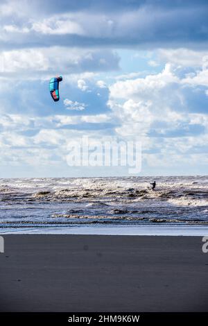 Ein Kitesurfer genießt seinen Sport am Strand von Ainsdale in der Nähe von Southport, Großbritannien. Stockfoto