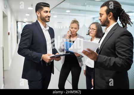 Während der Pause sprechen Geschäftsleute im Flur des Büros miteinander Stockfoto