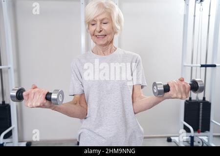 Hantelhanteln mit beiden Händen und lächelnd Stockfoto
