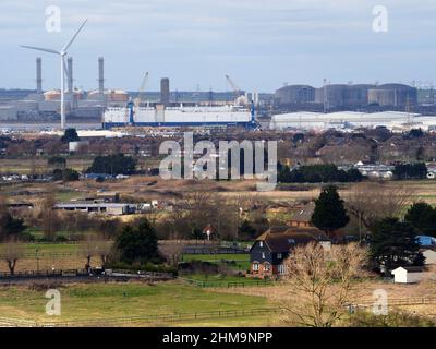 Minster on Sea, Kent, Großbritannien. 4th. Februar 2022. Die riesigen Betongasspeichertanks des National Grid (oben rechts) in ihrer Isle of Grain-Anlage (Europas größter LNG-Speicher), die heute von Minster on Sea, Kent, aus gesehen wird, da die britischen Energiepreise weiter steigen. Der Fahrzeugträger „Viking Amber“ wird bei Sheerness mit einer Erneuerungs-Energieturbine im Hafen von Sheerness als Größenvergleich gesehen. Kredit: James Bell/Alamy Live Nachrichten Stockfoto