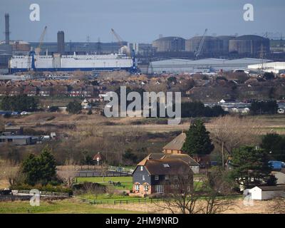 Minster on Sea, Kent, Großbritannien. 4th. Februar 2022. Die riesigen Betongasspeichertanks des National Grid (oben rechts) in ihrer Isle of Grain-Anlage (Europas größter LNG-Speicher), die heute von Minster on Sea, Kent, aus gesehen wird, da die britischen Energiepreise weiter steigen. Der Fahrzeugträger „Viking Amber“ ist am Hafen von Sheerness angelegter und gibt ein Gefühl der Größe. Kredit: James Bell/Alamy Live Nachrichten Stockfoto