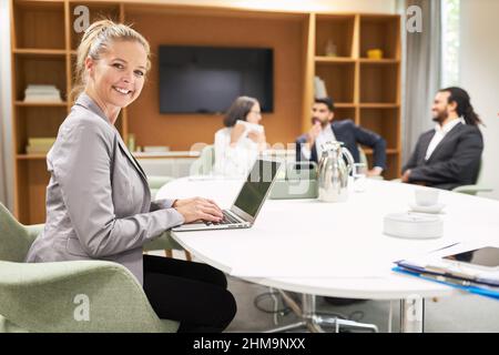 Glückliche junge Frau als erfolgreiche Geschäftsfrau am Laptop-Computer im Businessmeeting Stockfoto