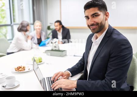 Zufriedener Geschäftsmann als Start-up-Gründer arbeitet im Konferenzraum am Laptop-Computer Stockfoto