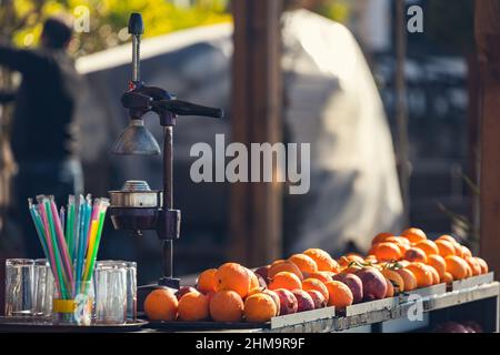 Nahaufnahme eines manuellen Entsafters aus Metall und einer Menge frischer Orangen auf dem Ladentisch Stockfoto