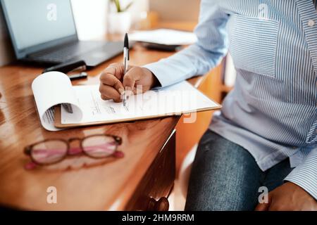 Eine Millionen-Dollar-Unterschrift. Eine kurze Aufnahme einer Geschäftsfrau, die an ihrem Schreibtisch Papierkram ausfüllte. Stockfoto