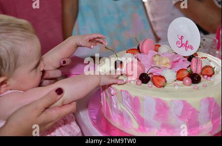 Mädchen neugeborenen 1-jährigen mit Händen berühren Kuchen während der Geburtstagsparty Stockfoto