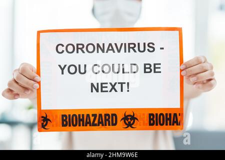 Mit Liebe und Gewahrsein werden wir das Coronavirus besiegen. Aufnahme einer Frau, die ein Schild mit der Aufschrift CORONAVIRUS hochhält - DU KÖNNTEST ALS NÄCHSTER dabei sein. Stockfoto