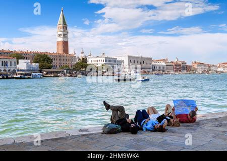 VENEDIG, ITALIEN - 18. MAI 2018: Eine Gruppe von nicht identifizierten Touristen ruht am Ufer des Canale Grande mit einer Karte der Stadt. Stockfoto